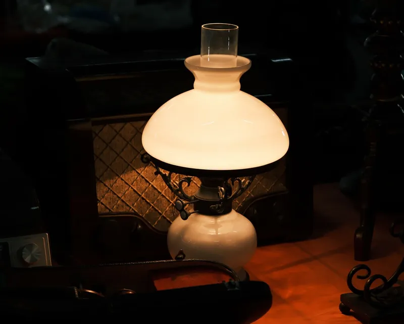 A warm milk-glass lamp glowing softly in a dark, quiet room at night